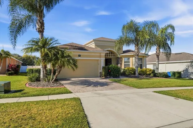 a view of a white house with a yard and palm trees