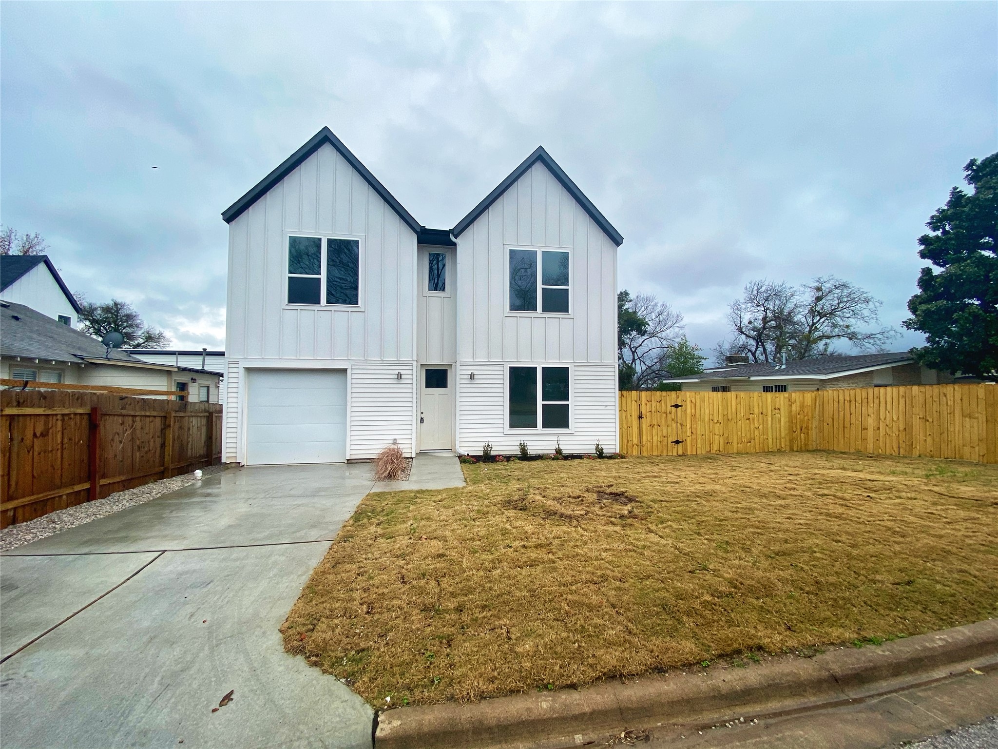 1916 Webberville Road, Unit B Austin, TX 78721 - Photo 2 of 25 Modern two-story residence featuring a white vertical and horizontal siding facade, dark trim, and multiple windows