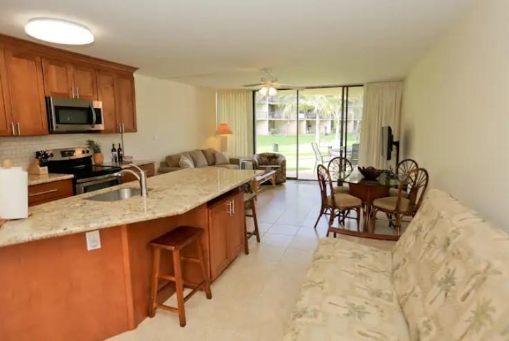 1032 South Kihei Road, Unit A103 Kihei, HI 96753 - Photo 14 of 48 a kitchen with granite countertop a sink a stove a table and chairs