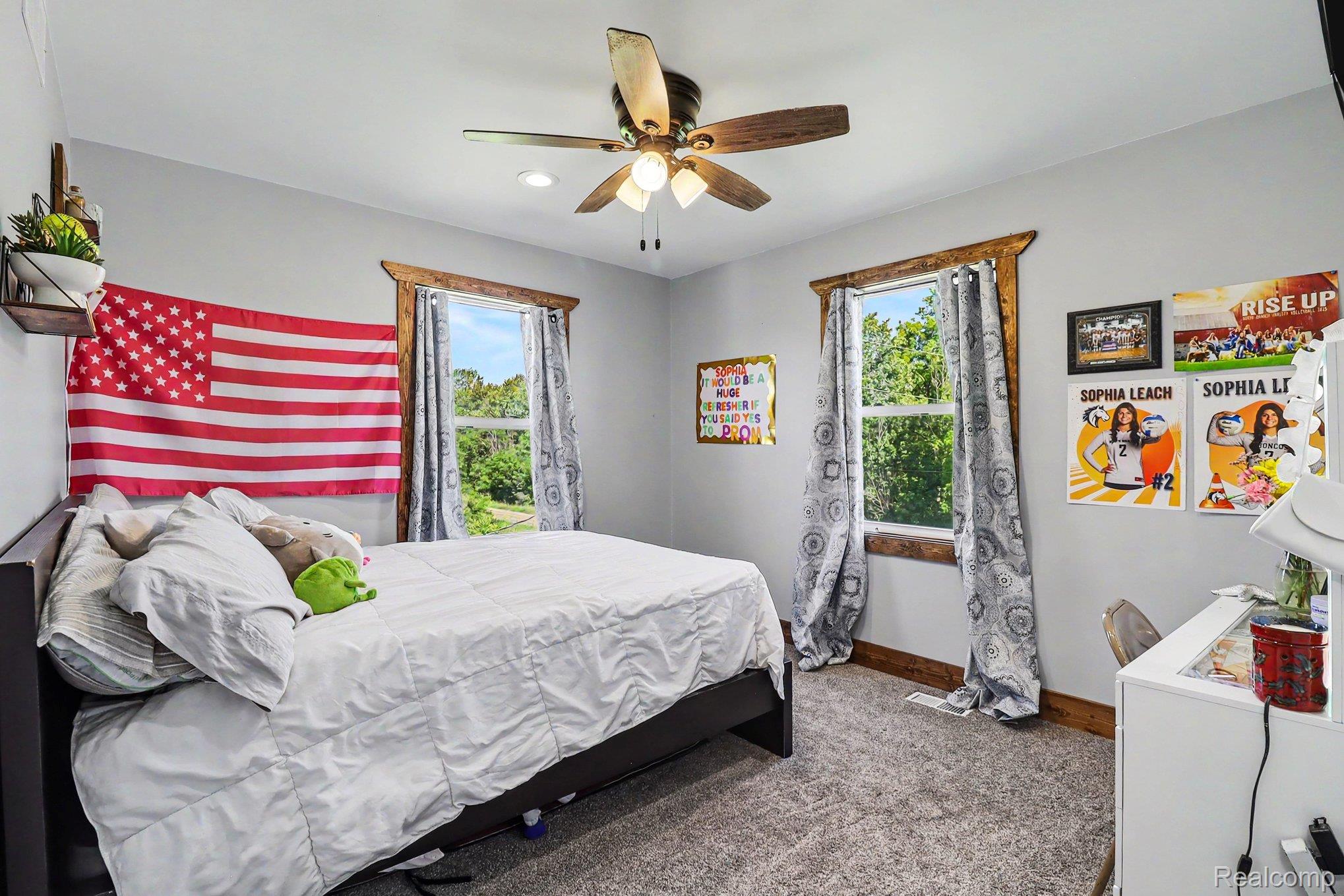 2150 East Snover Road Mayville, MI 48744 - Photo 25 of 48 Spacious room featuring two windows with natural wood trim, a ceiling fan with integrated lighting, and carpeted flooring