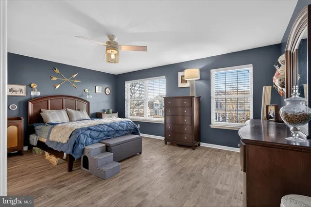 a bedroom with a bed and dresser with wooden floor