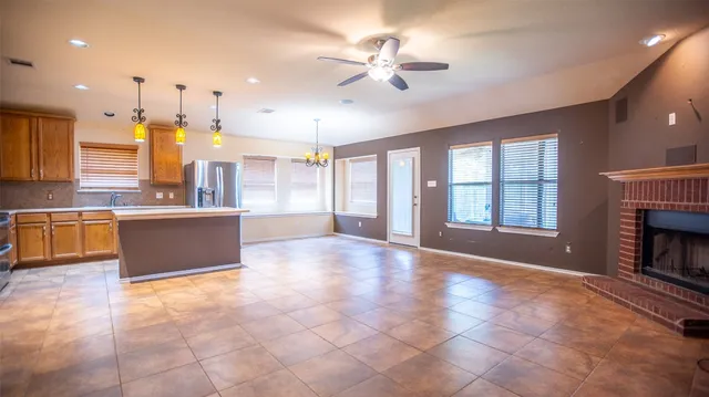 a large kitchen with stainless steel appliances granite countertop a stove top oven a sink dishwasher and a fireplace with wooden floor