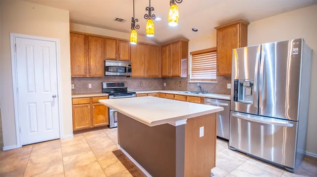 a kitchen with stainless steel appliances granite countertop a refrigerator a stove a sink dishwasher and a refrigerator with wooden floor