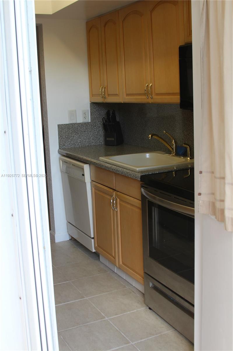 1300 North Ocean Boulevard, Unit 111 Pompano Beach, FL 33062 - Photo 3 of 26 a kitchen with granite countertop white cabinets and stainless steel appliances