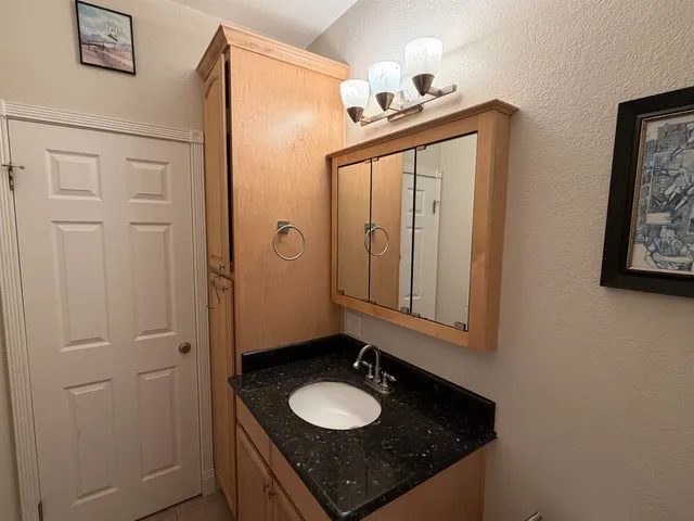 a bathroom with a granite countertop sink and a mirror