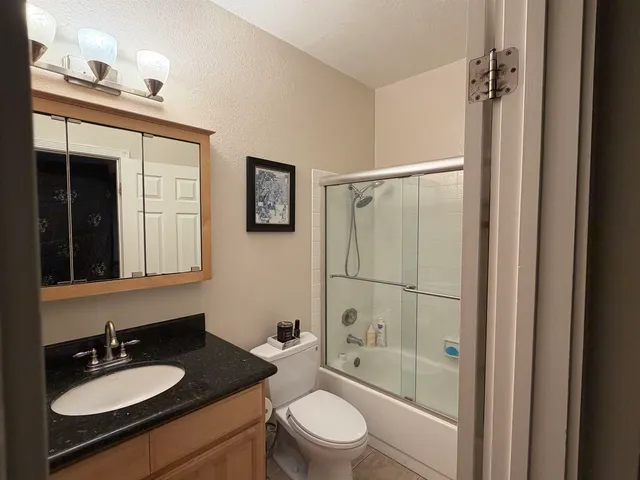 a bathroom with a granite countertop sink toilet a mirror and shower