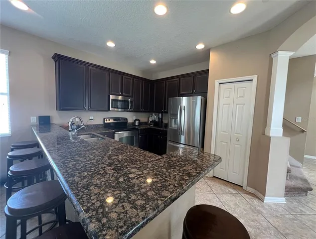 a kitchen with stainless steel appliances granite countertop a refrigerator a stove and a sink with wooden cabinets