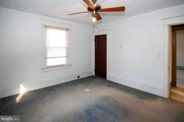 an empty room with a chandelier fan and closet