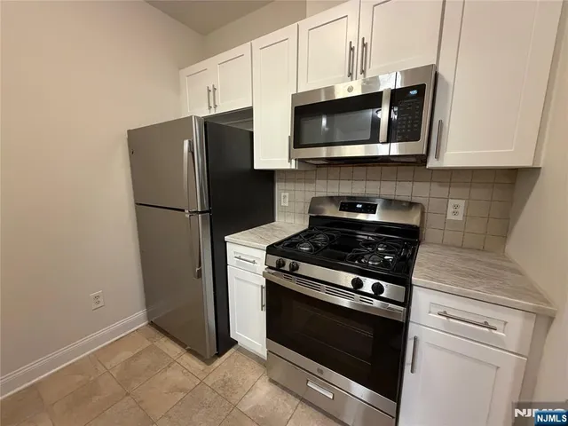 a kitchen with stainless steel appliances white cabinets and a stove top oven