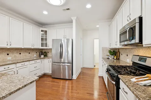 a kitchen with granite countertop white cabinets and stainless steel appliances
