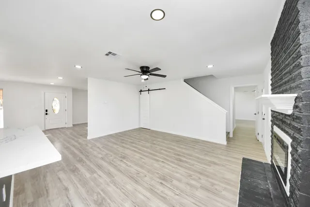 an empty room with wooden floor and a ceiling fan
