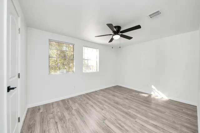a view of empty room with wooden floor and fan