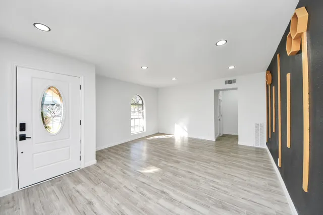 a view of an empty room with wooden floor and a window