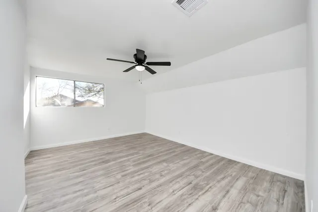 a view of empty room with wooden floor and fan