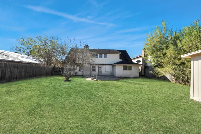 a view of a house with a big yard plants and large trees