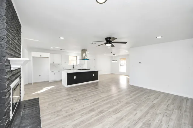 a large white kitchen with a sink and dishwasher a kitchen island with wooden floor