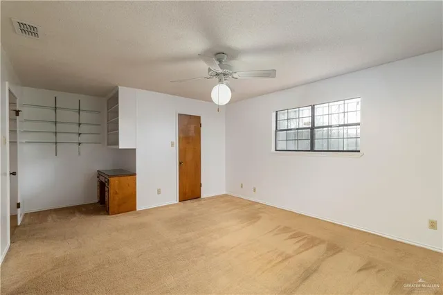 an empty room with windows and ceiling fan