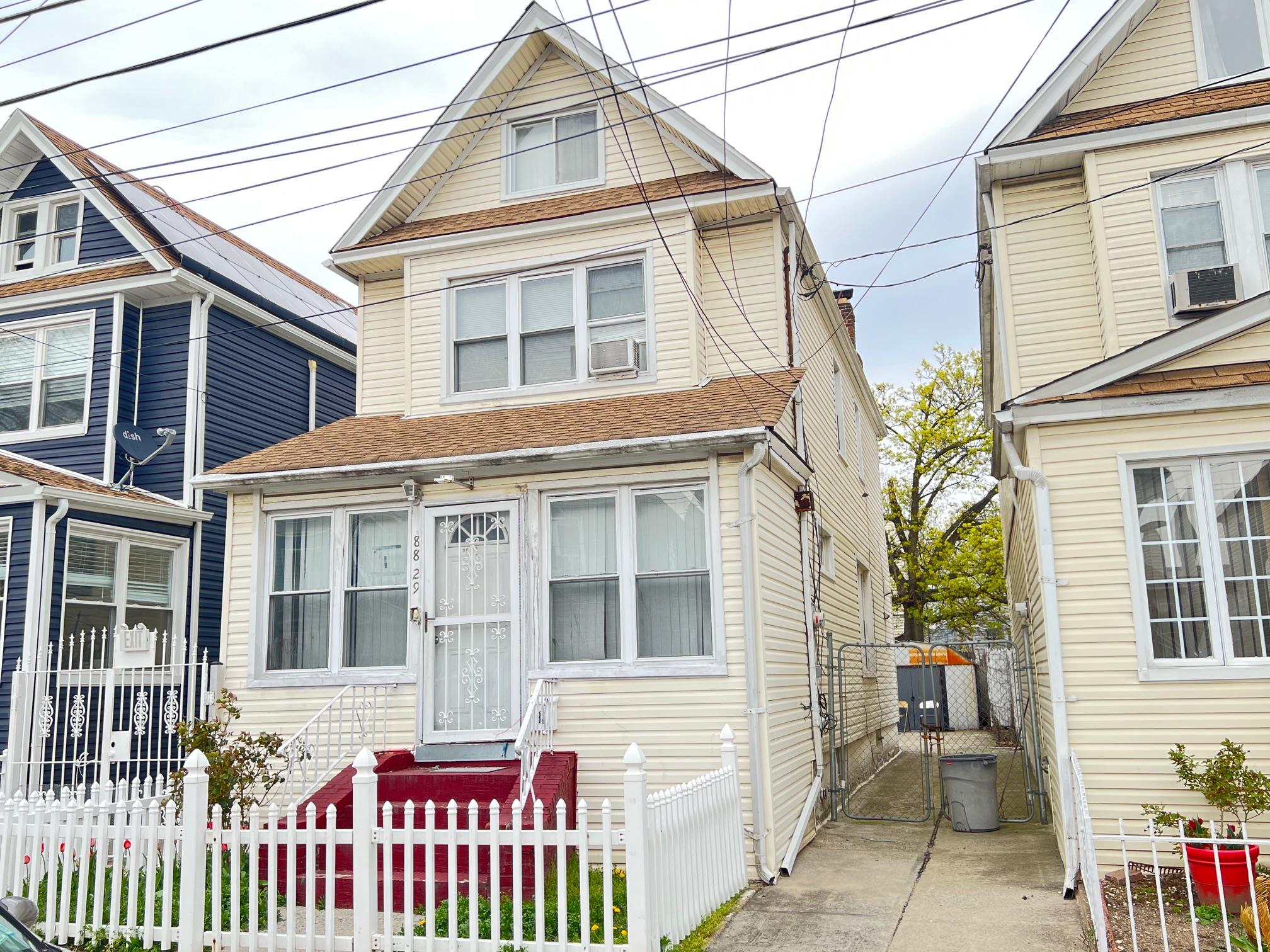 a view of a house with a small yard and wooden fence