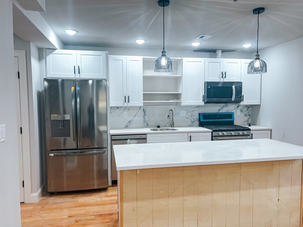 a kitchen with kitchen island a counter top space stainless steel appliances and wooden floor