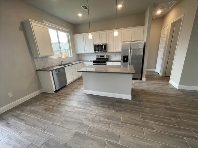 a kitchen with stainless steel appliances granite countertop a refrigerator a sink a stove a microwave and island