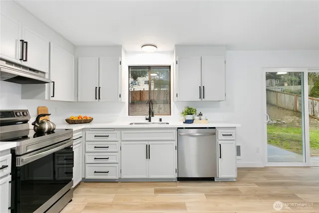 a kitchen with stainless steel appliances a stove a sink and white cabinets