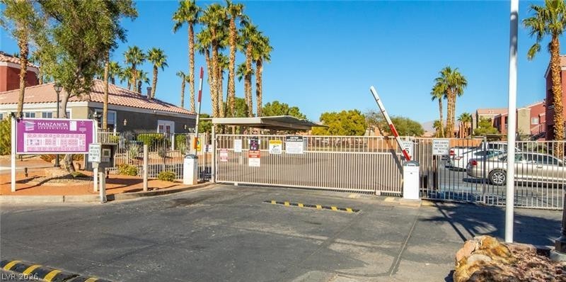 4730 East Craig Road, Unit 2142 Las Vegas, NV 89115 - Photo 8 of 8 Secure community entrance featuring a gate and ample parking, surrounded by mature palm trees.