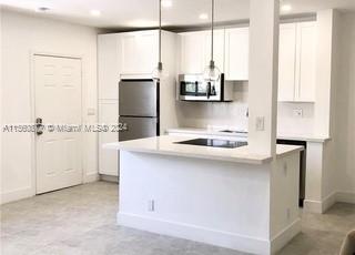 a kitchen with kitchen island a sink appliances and cabinets