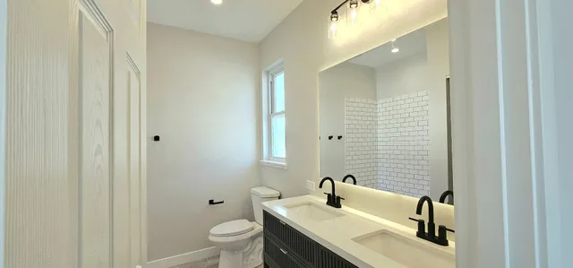 a bathroom with a granite countertop sink toilet and mirror