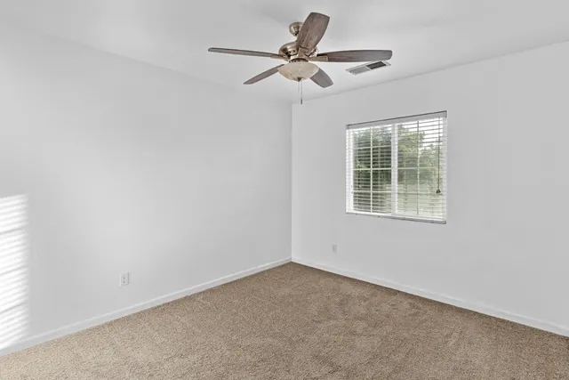 an empty room with a window and a fan