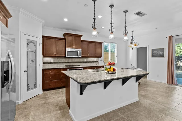 a kitchen with stainless steel appliances a sink a counter top space cabinets and refrigerator