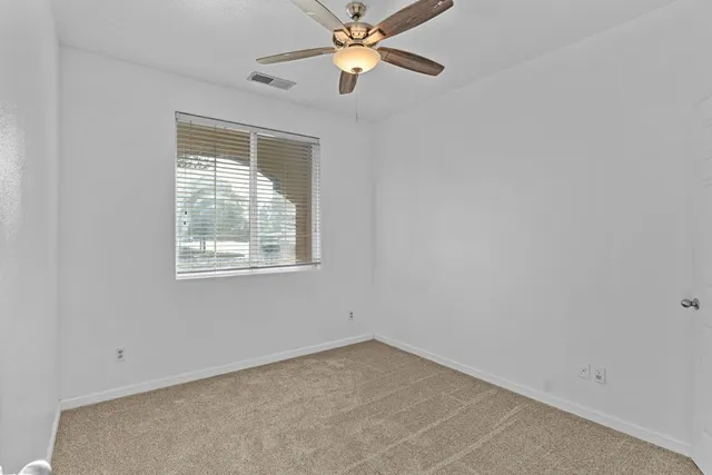 an empty room with a window and a fan
