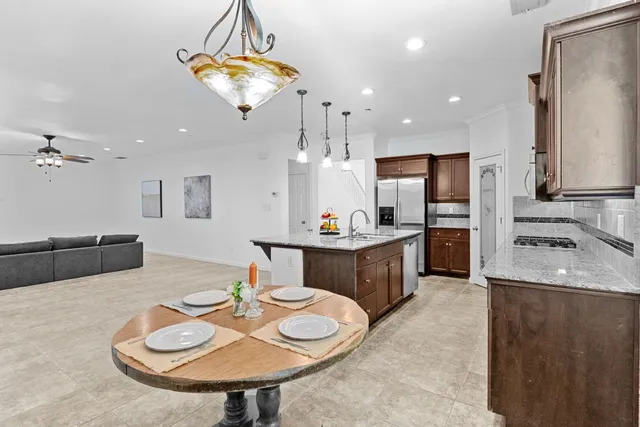 a kitchen with stainless steel appliances kitchen island granite countertop a sink and a refrigerator