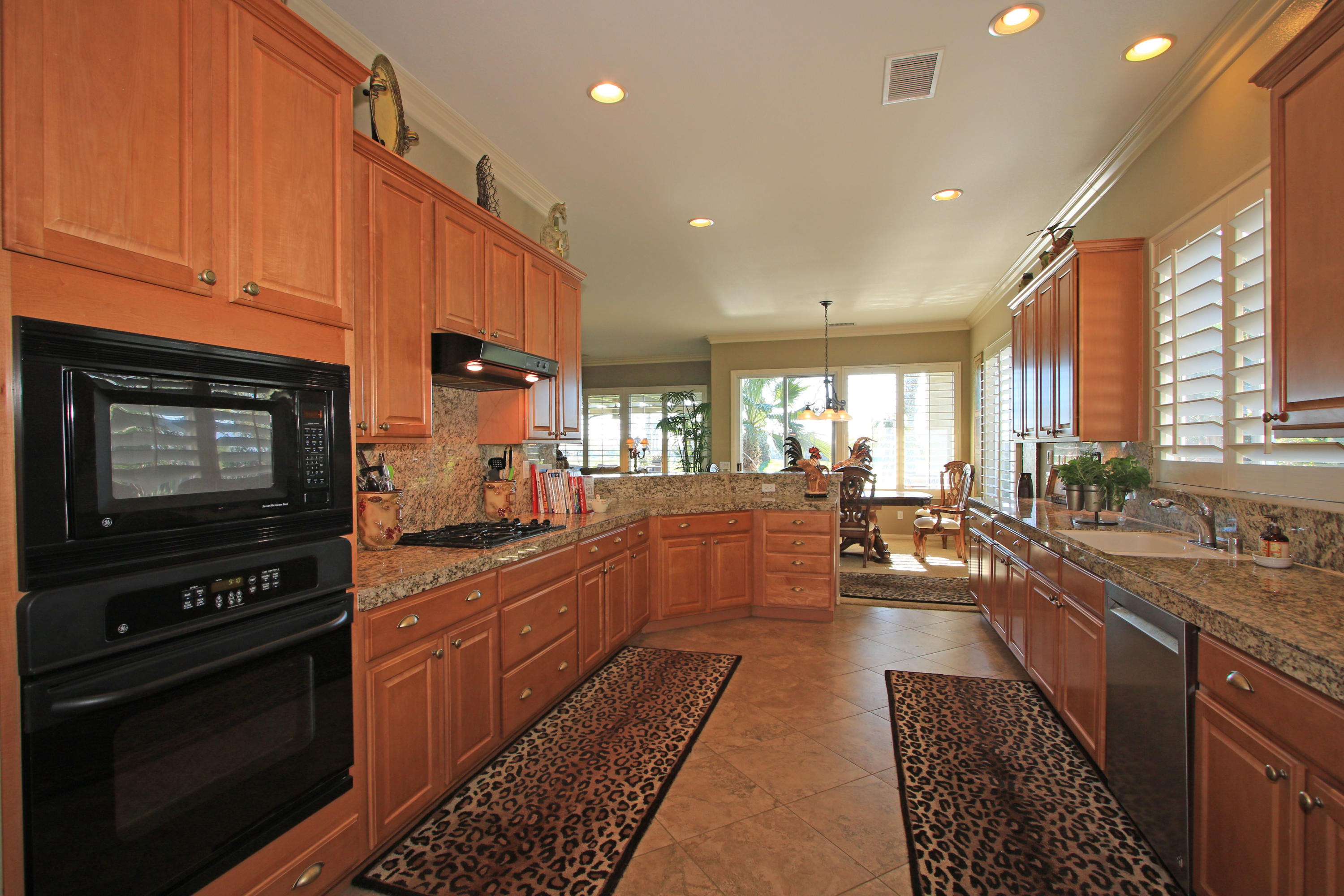 44530 Knightswood Road Indio, CA 92201 - Photo 12 of 38 a kitchen with stainless steel appliances kitchen island granite countertop a stove a sink dishwasher and cabinets with wooden floor