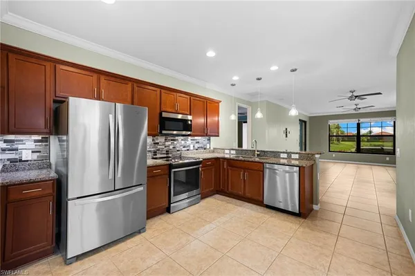 a large kitchen with stainless steel appliances granite countertop a refrigerator and a stove top oven
