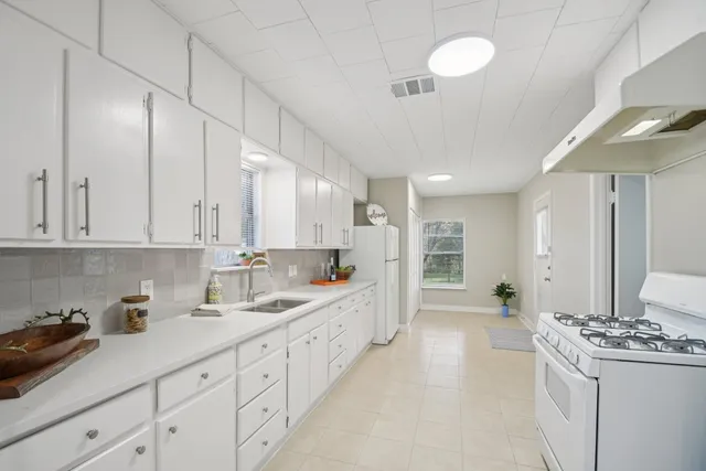 a large white kitchen with stainless steel appliances granite countertop a lot of counter space and a sink