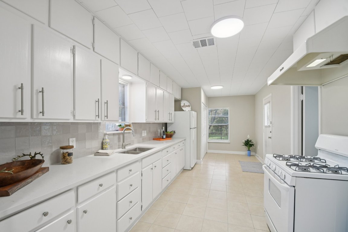 209 East 8th Street Elgin, TX 78621 - Photo 10 of 23 a large white kitchen with stainless steel appliances granite countertop a lot of counter space and a sink