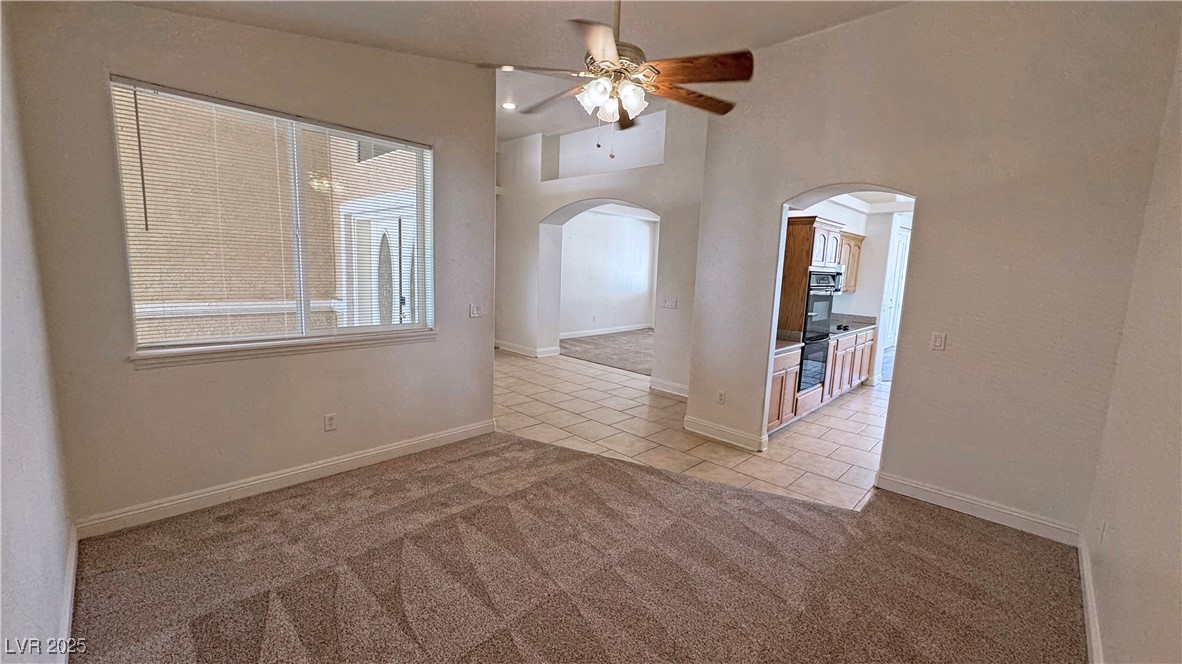 1771 Labrador Street Pahrump, NV 89048 - Photo 14 of 64 Empty room featuring arched walkways, ceiling fan, light tile patterned floors, and light carpet