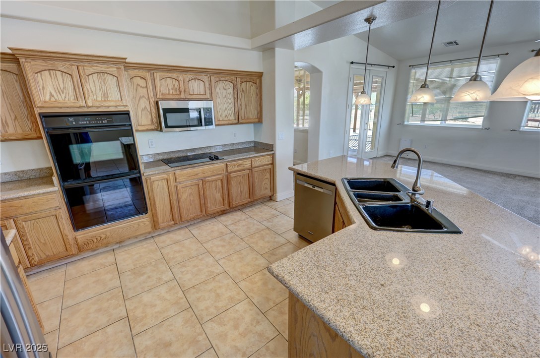1771 Labrador Street Pahrump, NV 89048 - Photo 16 of 64 Kitchen featuring black appliances, arched walkways, healthy amount of natural light, decorative light fixtures, and vaulted ceiling