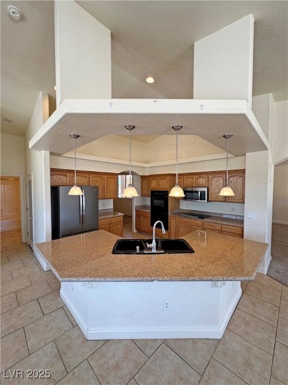 1771 Labrador Street Pahrump, NV 89048 - Photo 17 of 64 Kitchen with black appliances, brown cabinets, a large island with sink, light tile patterned flooring, and recessed lighting