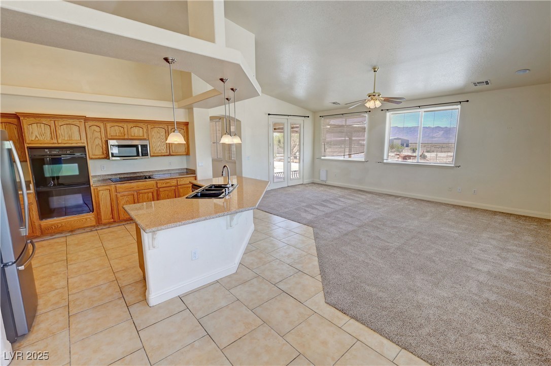1771 Labrador Street Pahrump, NV 89048 - Photo 18 of 64 Kitchen with black appliances, healthy amount of natural light, ceiling fan, light carpet, and high vaulted ceiling
