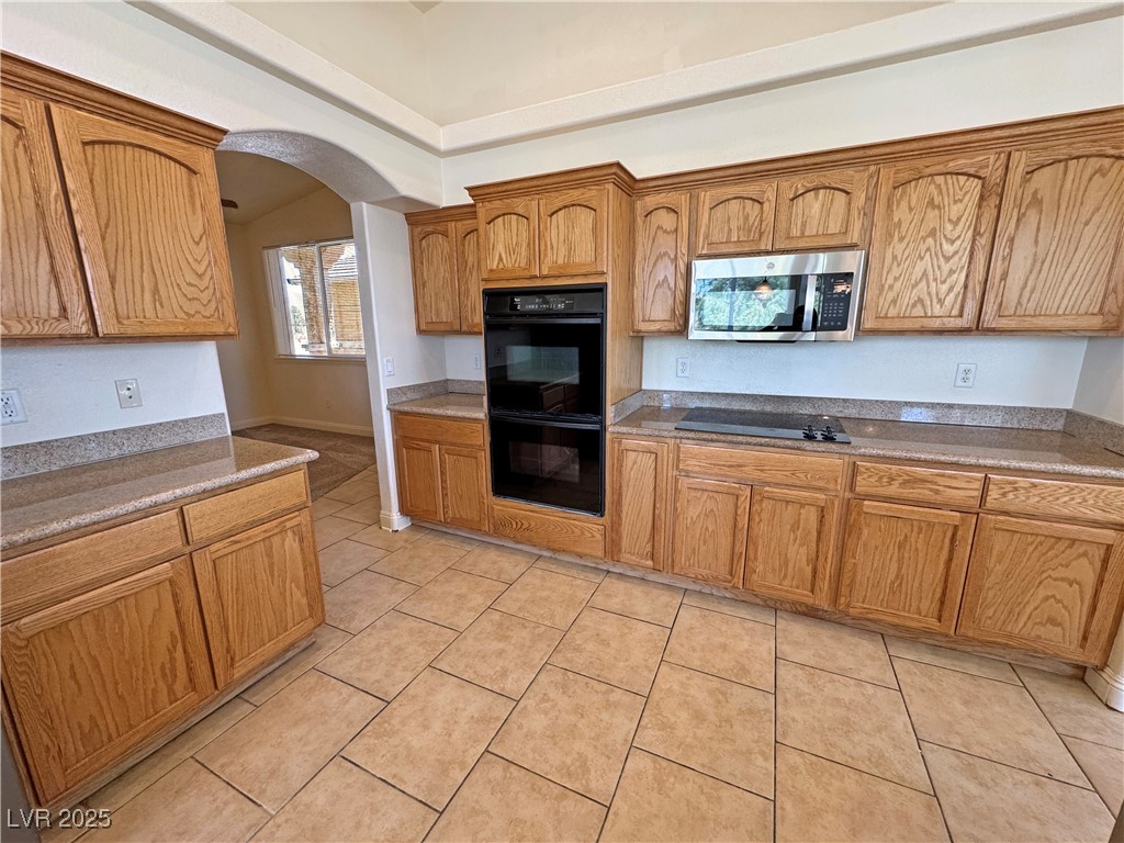 1771 Labrador Street Pahrump, NV 89048 - Photo 19 of 64 Kitchen with black appliances, arched walkways, light tile patterned flooring, and brown cabinets