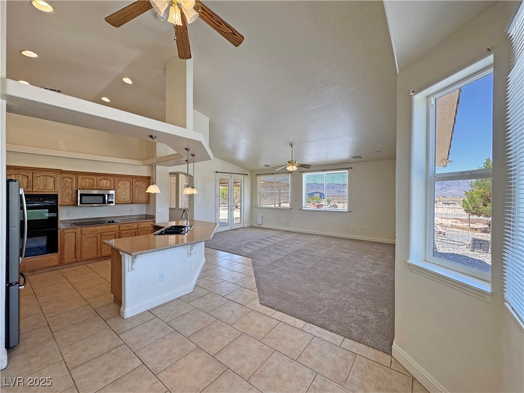 1771 Labrador Street Pahrump, NV 89048 - Photo 21 of 64 Kitchen with a ceiling fan, black appliances, light carpet, light tile patterned flooring, and a textured ceiling
