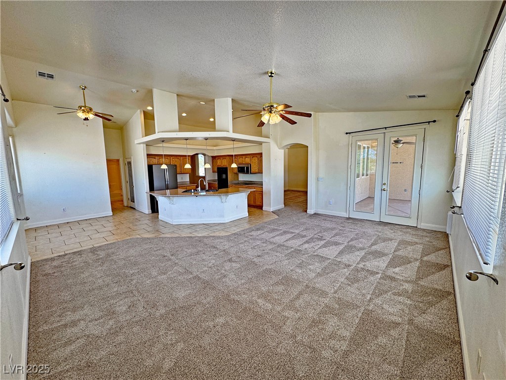 1771 Labrador Street Pahrump, NV 89048 - Photo 25 of 64 Unfurnished living room with a ceiling fan, plenty of natural light, arched walkways, and a textured ceiling