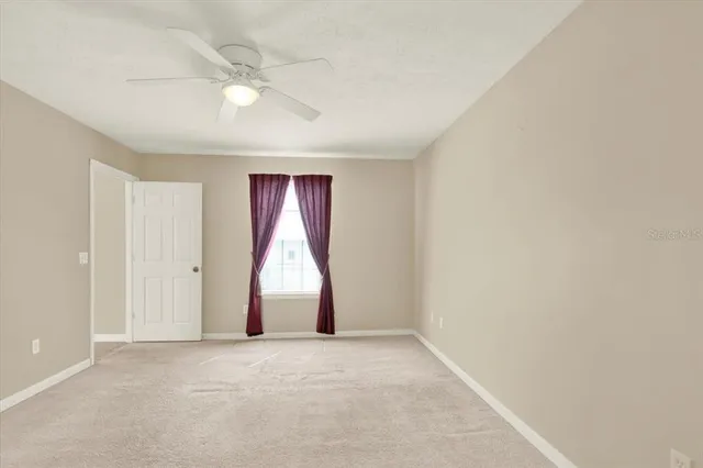 an empty room with a window and a ceiling fan