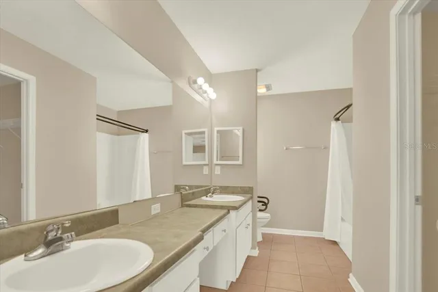 a bathroom with a granite countertop double vanity sink and mirror