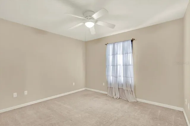 an empty room with windows and ceiling fan