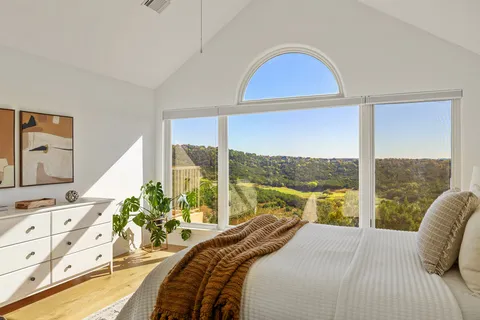 a bedroom with a balcony a bed and a large window
