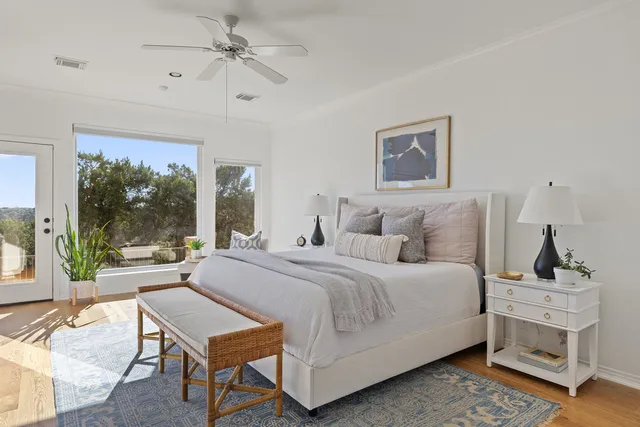 a bedroom with a bed a large window and potted plant on the dresser