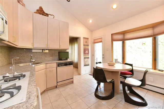 a kitchen with stainless steel appliances kitchen island granite countertop a table chairs in it and a window