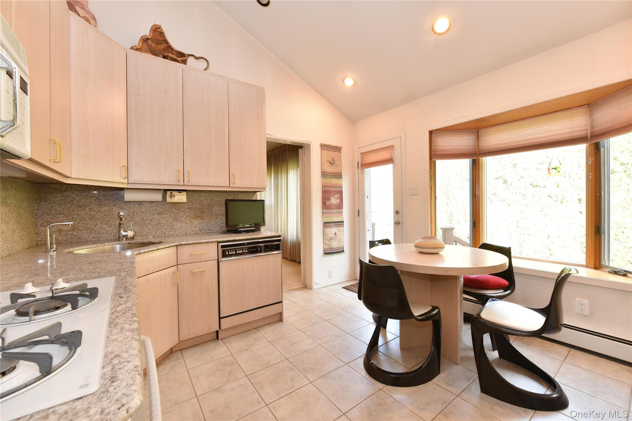 217-49 Stewart Road Queens, NY 11364 - Photo 16 of 27 a kitchen with stainless steel appliances kitchen island granite countertop a table chairs in it and a window